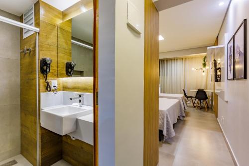 a bathroom with a sink and a room with a table at Apart Hotel Centro de Brasília in Brasilia