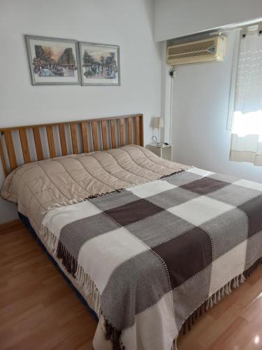 a bed in a bedroom with a checkered blanket at Departamento Ricchieri 743 in Rosario