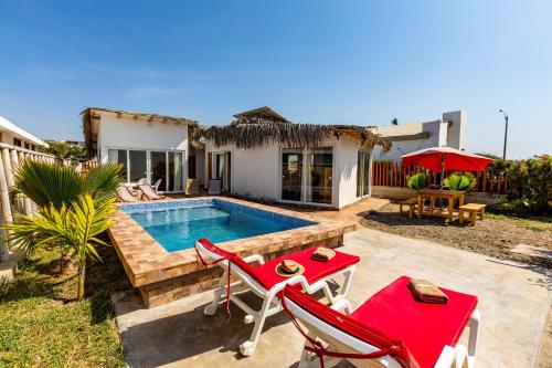 a house with a swimming pool and two red chairs at Casa Killa Vichayito in Vichayito