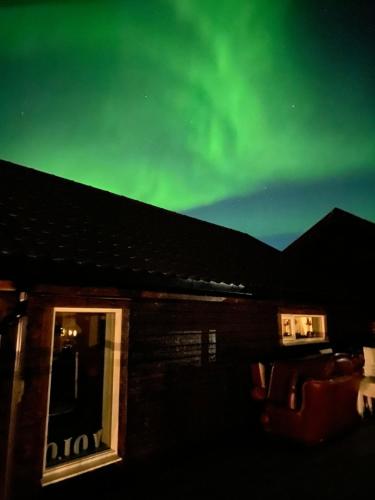 an image of the aurora in the sky above a house at In the heart of the Lyngen alps, Holmen i Lyngen in Lyngseidet