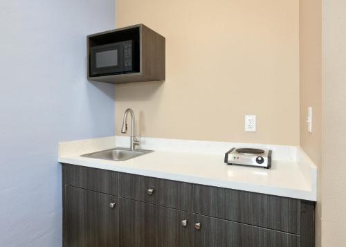 a kitchen with a sink and a microwave at Super 8 by Wyndham Victoria - South - Hwy 59 in Victoria