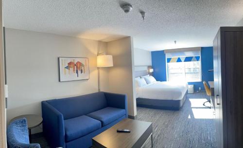 Habitación de hotel con sofá azul y cama en Holiday Inn Express & Suites Marquette, an IHG Hotel en Marquette