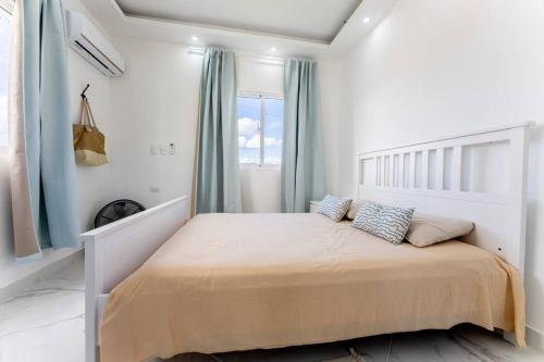 a bedroom with a large bed with blue curtains at Larimar 302 - Bayahibe in Bayahibe