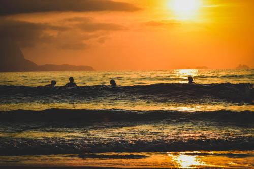 a group of people in the ocean at sunset at Longboard Paradise Surf Club in Rio de Janeiro