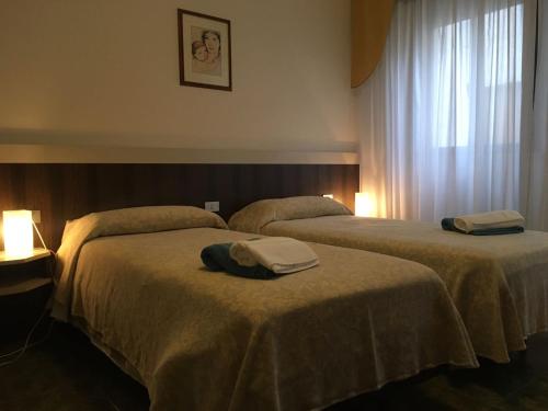 two beds in a hotel room with towels on them at Hotel Centrale in Este