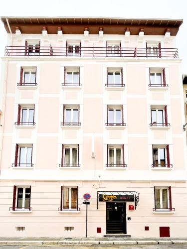 a white building with a door in front of it at Hôtel Gloria in Grenoble