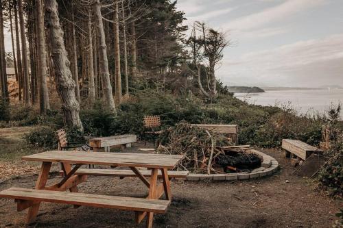 a picnic table and benches next to the water at Treehouse on the Water -Eagles Nest-20 ft high in Port Angeles