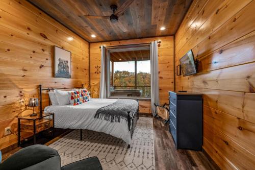 a bedroom with a bed in a room with wooden walls at The Overlook - '21 Cabin - Gorgeous Unobstructed Views - Fire Pit Table - GameRm - HotTub - Xbox - Lots of Bears in Gatlinburg