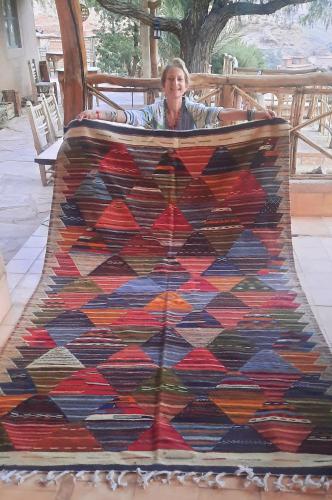 a woman laying on top of a colorful quilt at Maison d'Hôtes Irocha in Tisselday
