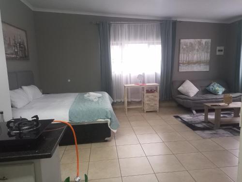 a bedroom with a bed and a couch and a window at Menlyn Mews Guesthouse in Pretoria