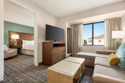 a hotel room with a bed and a flat screen tv at Staybridge Suites Oklahoma City-Quail Springs by IHG in Oklahoma City