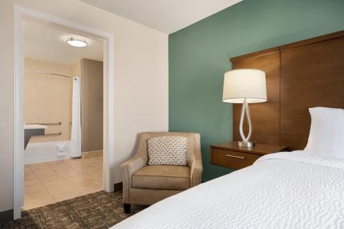 a bedroom with a bed and a chair and a lamp at Staybridge Suites Oklahoma City-Quail Springs by IHG in Oklahoma City