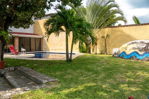 une cour avec un palmier et une piscine dans l'établissement Casa Madero, à Oacalco