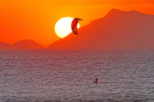 a person kite surfing in the ocean at sunset at Longboard Paradise Surf Club in Rio de Janeiro