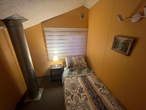 a small bedroom with a bed and a window at Hostal Mirador Quellón in Quellón