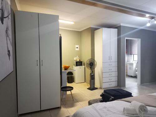 a bedroom with a bed and a room with a kitchen at Menlyn Mews Guesthouse in Pretoria