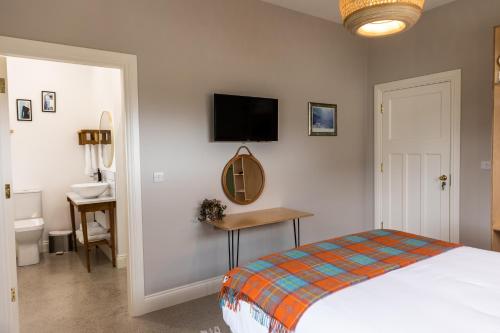 a bedroom with a bed and a desk and a television at Aiteall Bed and Breakfast in Liscannor