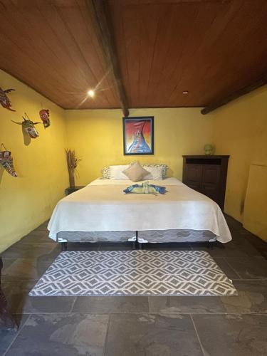 a bedroom with a large bed in a yellow wall at Johnnys Place Hotel in Monterrico
