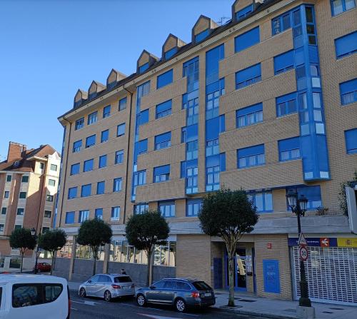 un gran edificio con coches estacionados frente a él en LA ERIA I, muy soleado, Wifi, garaje, 15 min a pie al centro, en Oviedo