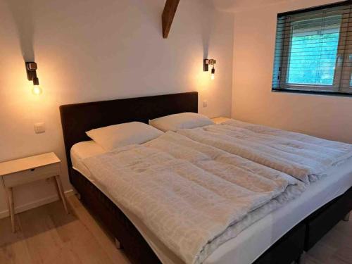 a bedroom with a large bed with white sheets at De Skure: vakantiewoning op boerderij in Harelbeke