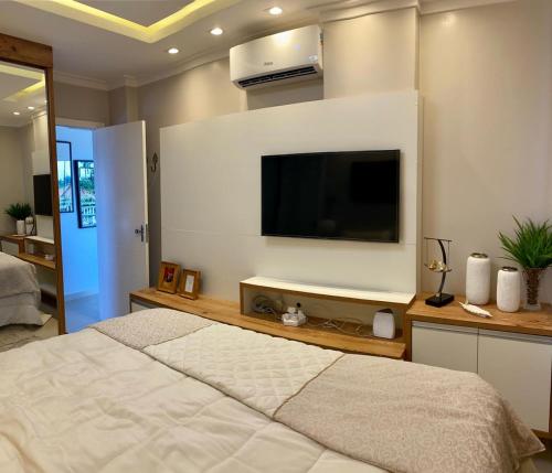a bedroom with a large bed and a flat screen tv at Apartamento para temporada mobiliado in Alter do Chao