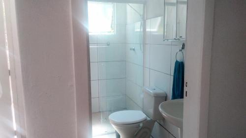 Baño blanco con aseo y lavamanos en Casa Praia de Mariscal, en Bombinhas
