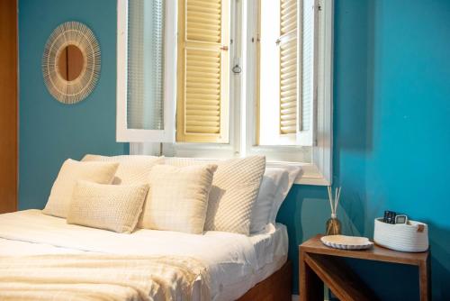 a bedroom with a bed with blue walls and windows at Longboard Paradise Surf Club in Rio de Janeiro
