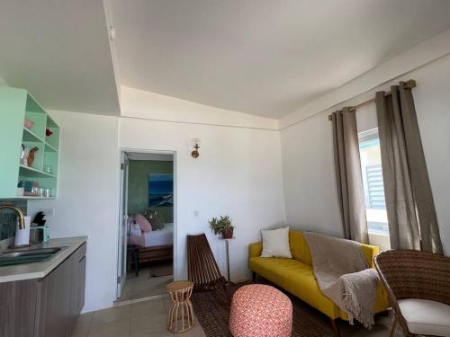 a living room with a yellow couch and a kitchen at Casita Del Mar Oceanfront Romantic Retreat In Islote in Arecibo