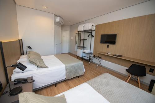 a hotel room with two beds and a flat screen tv at Origens Hotel in São Luiz Gonzaga