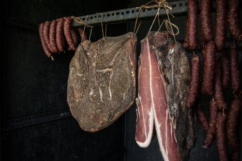 a bunch of meat hanging on a rack with bacon at Sonnenhotel Adler Spa & Nature Adults only in Villandro