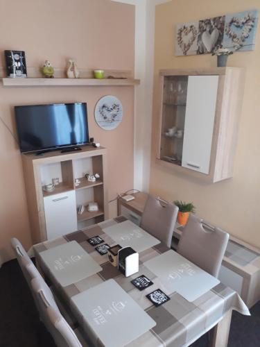 a dining room table with chairs and a television at Penzion Romance in Vyšší Brod