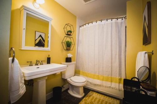 a yellow bathroom with a sink and a toilet at Spacious Loft Over Coffee Shop - Romantic Downtown Escape in Greeley