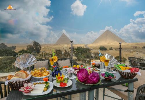 カイロにあるPANORAMA view pyramidsのピラミッドを背景に食べ物が詰まったテーブル