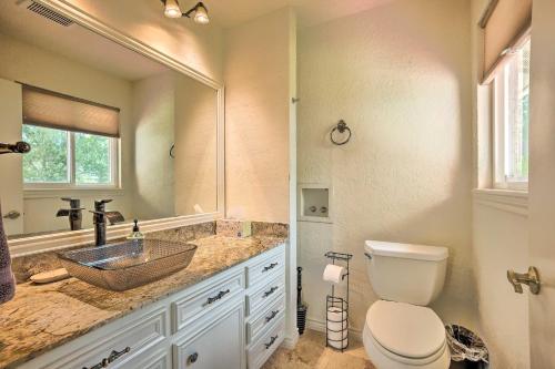a bathroom with a sink and a toilet and a mirror at Modern Lake Conroe House with Lakefront Park and Deck! in Willis