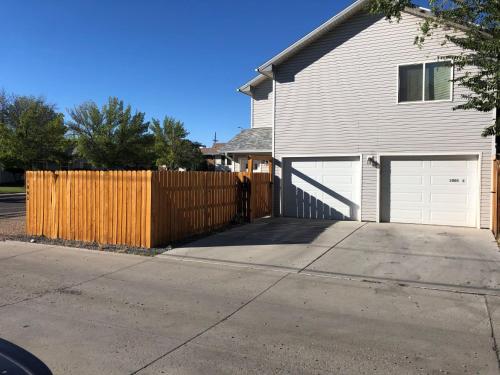 a house with a wooden fence and a driveway at Cozy Studio in Grand Junction