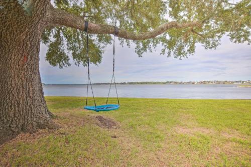 a blue swing hanging from a tree next to the water at Modern Lake Conroe House with Lakefront Park and Deck! in Willis