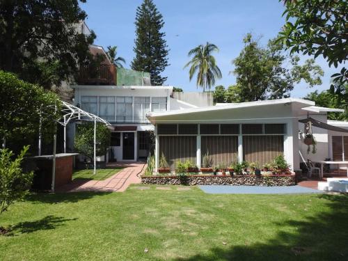a white house with a lawn in front of it at Habitación independiente a pie del lago con AC in Tequesquitengo