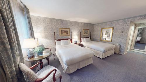 a hotel room with two beds and a chair at Avon Old Farms Hotel in Avon