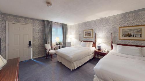 a hotel room with two beds and a door at Avon Old Farms Hotel in Avon