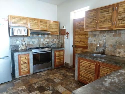 cocina con armarios de madera, fogones y nevera en CASA KILLA, Canoas de Punta Sal, en Canoas