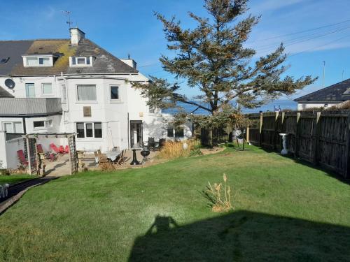 a yard with a tree and a white house at Beach lodge Stunning Sea Views in Portballintrae