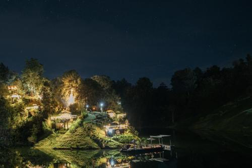 a night view of a resort on a hill next to a river at Domus Glamping Guatapé in Guatapé