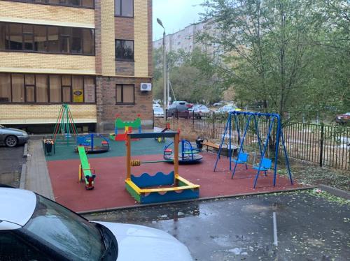 a playground in a parking lot next to a building at Scandi Home in Uralsk