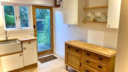 a kitchen with white cabinets and a sink and a window at Dove Cottage in Newbridge on Wye