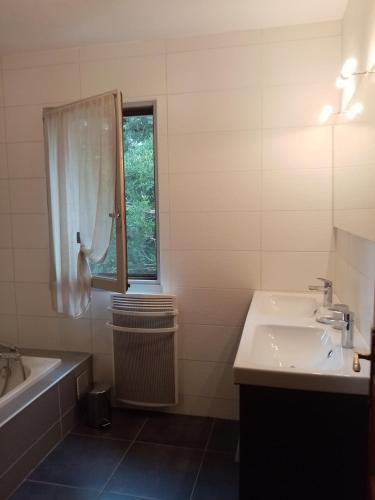 La salle de bains blanche est pourvue d'un lavabo, d'une baignoire et d'une fenêtre. dans l'établissement Maison à la campagne, à Duffort