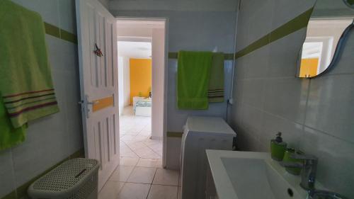 y baño con lavabo, aseo y toallas verdes. en Villa Campêche, en Bouillante