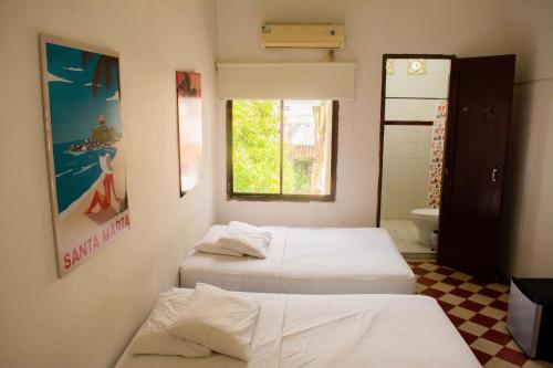 a room with three beds and a bathroom with a window at Hotel Miami SM in Santa Marta
