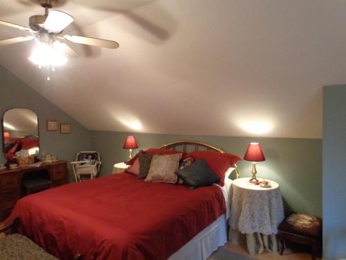 1 dormitorio con cama roja y ventilador de techo en Tea Cozy Bed & Breakfast en Qualicum Beach