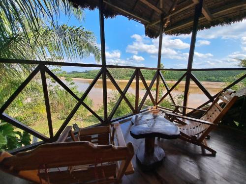 a porch with chairs and a view of a river at Andean Wings Sotupa Eco Lodge in Puerto Maldonado