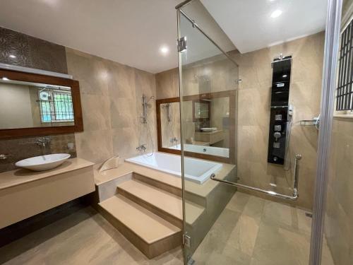 a bathroom with a shower and a sink and a tub at Yasuragi Boutique Resort in Shencottah